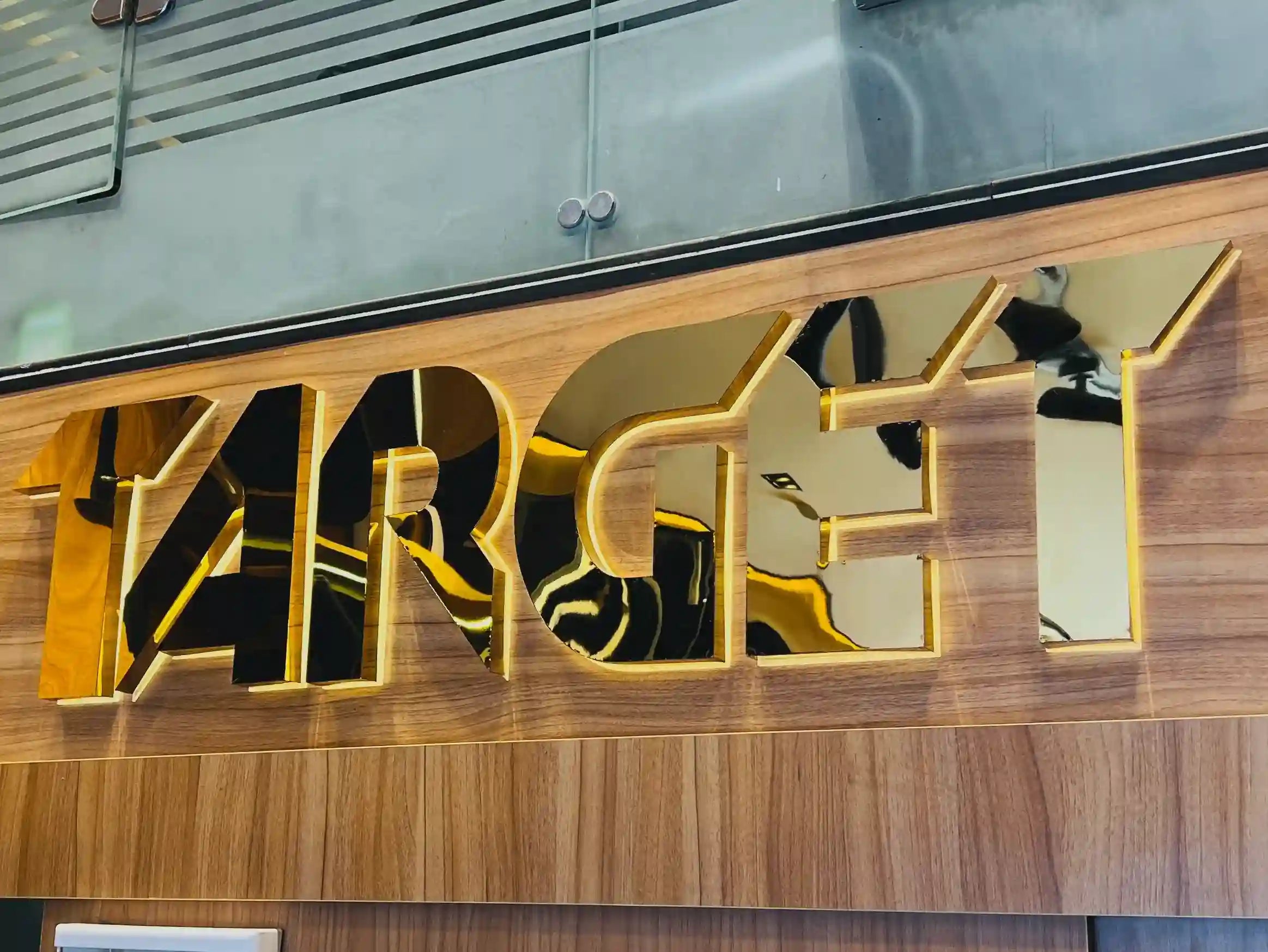 Gold 'TARGET' logo on a wooden surface